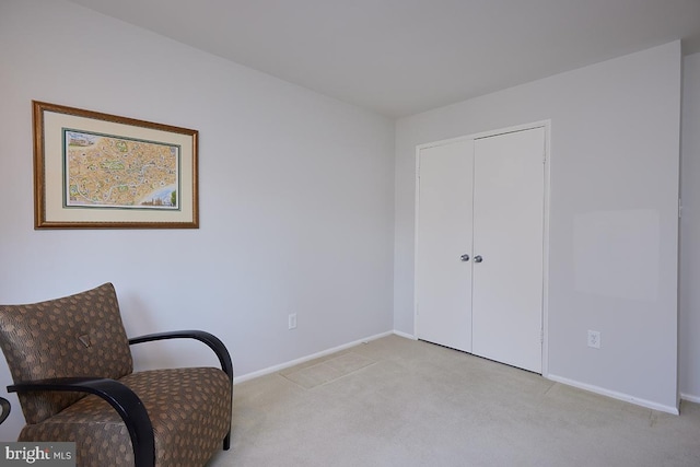 living area featuring baseboards and light colored carpet