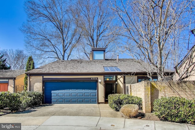 view of front facade featuring a garage, brick siding, driveway, and fence