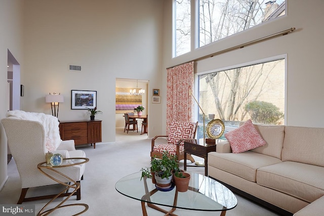 living room with a chandelier, visible vents, carpet floors, and a towering ceiling