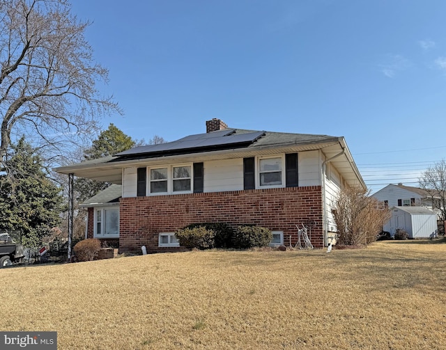 view of front of house featuring an outbuilding, brick siding, a storage unit, a chimney, and a front yard