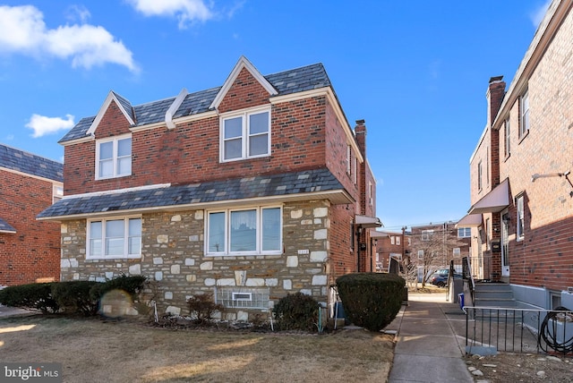 view of side of home featuring stone siding, a chimney, and a high end roof