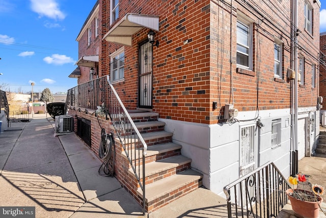 view of exterior entry with cooling unit and brick siding