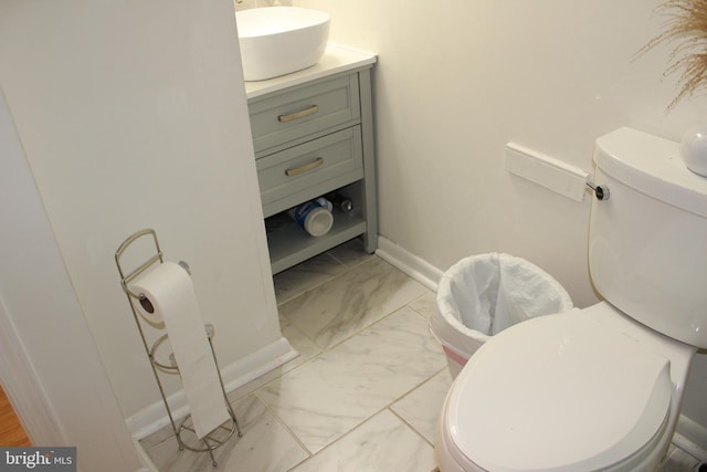 bathroom with baseboards, toilet, marble finish floor, and vanity