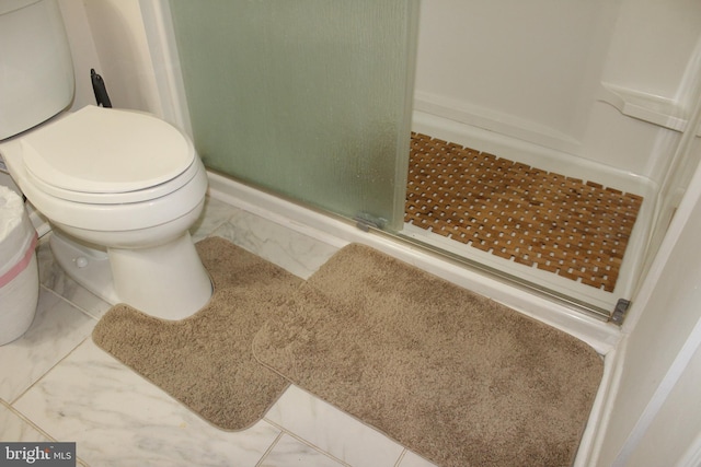 bathroom with marble finish floor, toilet, and a shower stall