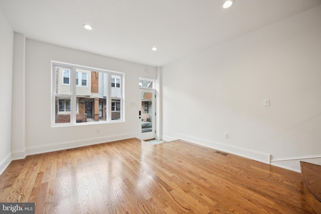 empty room featuring light wood-type flooring, visible vents, baseboards, and recessed lighting