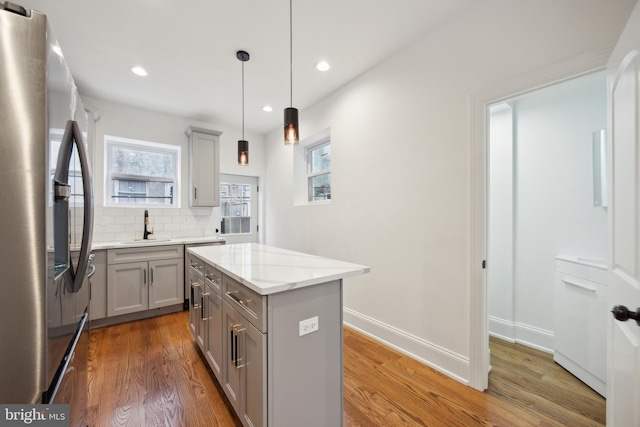 kitchen with a sink, light wood-type flooring, stainless steel refrigerator with ice dispenser, and gray cabinets