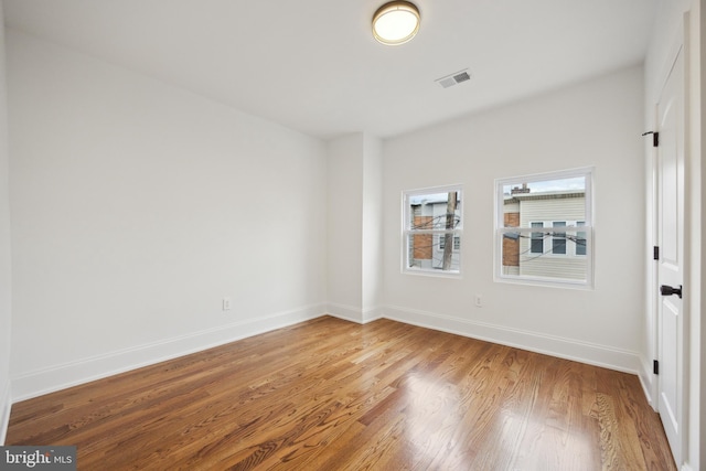 unfurnished room featuring baseboards, visible vents, and light wood-style floors