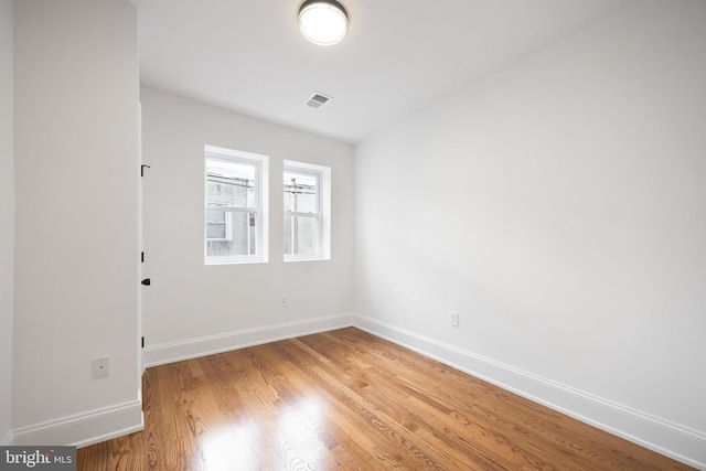 empty room with light wood-style floors, visible vents, and baseboards