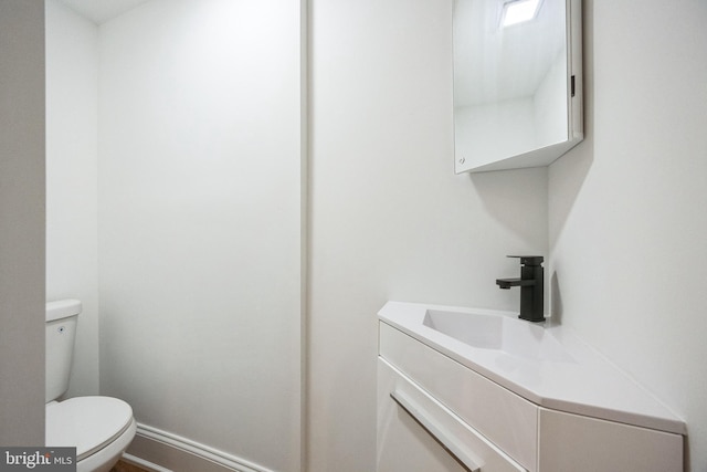 bathroom featuring vanity, toilet, and baseboards