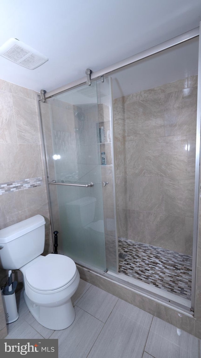 bathroom featuring a shower stall, toilet, and visible vents