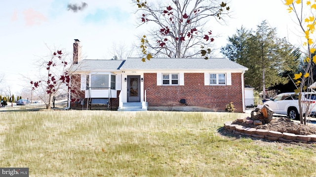 view of front facade with brick siding, entry steps, a chimney, and a front lawn