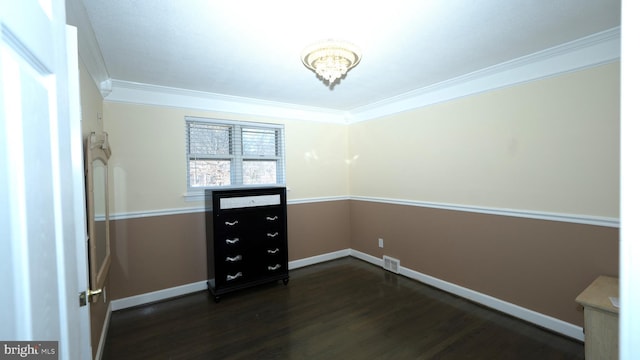 empty room featuring visible vents, baseboards, ornamental molding, dark wood-style floors, and a notable chandelier
