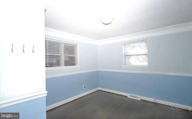 empty room with visible vents, baseboards, dark wood finished floors, and crown molding