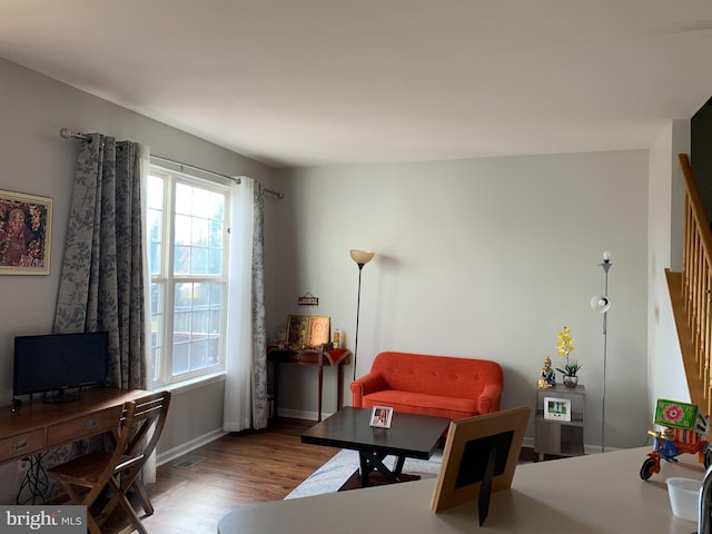 living area featuring baseboards, stairs, visible vents, and wood finished floors