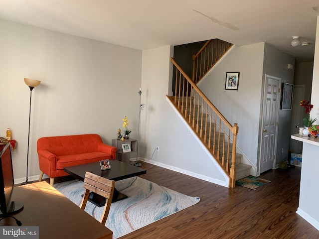 living area with baseboards, stairway, and wood finished floors