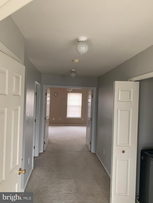 hall with baseboards and light colored carpet