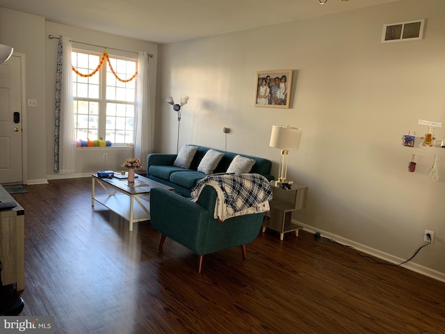 living room featuring dark wood-type flooring, visible vents, and baseboards