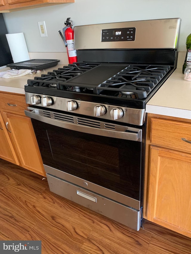 kitchen with stainless steel gas range, brown cabinets, and light countertops