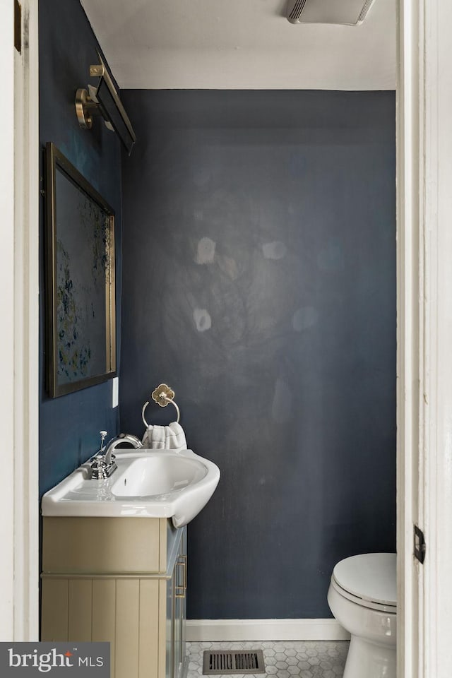 bathroom featuring toilet, vanity, visible vents, and baseboards