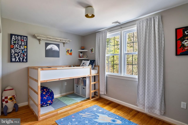 bedroom featuring visible vents, baseboards, and wood finished floors