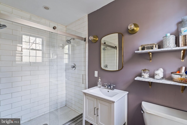 full bathroom featuring a stall shower, vanity, and toilet