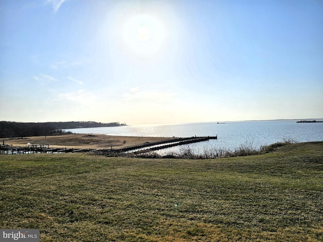 view of dock with a lawn and a water view