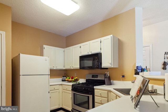 kitchen featuring stainless steel gas range oven, freestanding refrigerator, light countertops, a textured ceiling, and black microwave