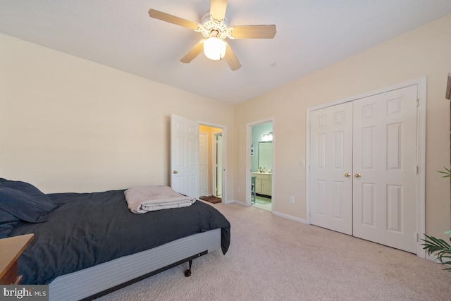 bedroom with ceiling fan, ensuite bathroom, light carpet, baseboards, and a closet