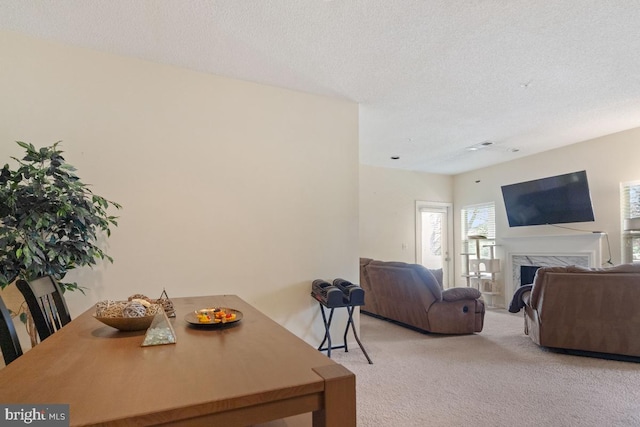 dining room featuring light carpet, a textured ceiling, and a premium fireplace