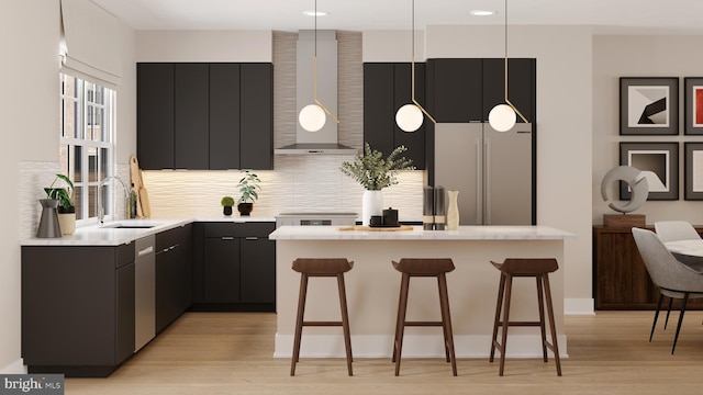 kitchen featuring a kitchen breakfast bar, light countertops, stainless steel appliances, wall chimney range hood, and a sink