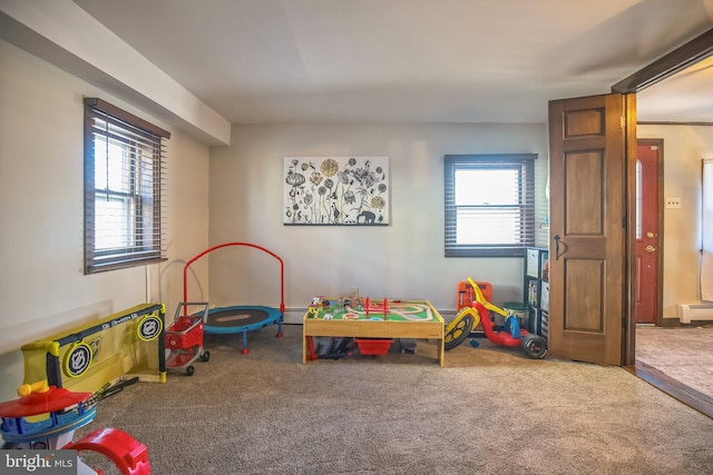 playroom with a baseboard radiator, carpet flooring, and a healthy amount of sunlight