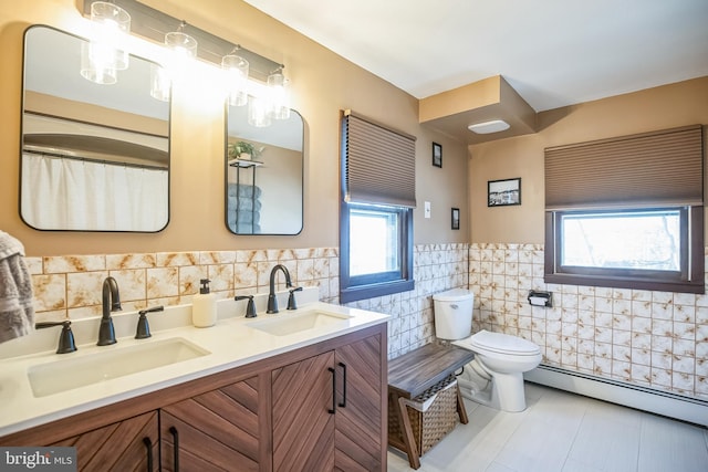 bathroom with a baseboard heating unit, a sink, toilet, and tile walls