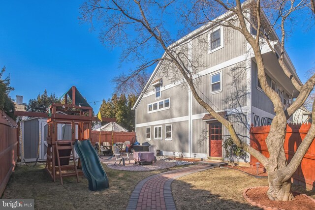 back of property with a playground, a patio, and a fenced backyard