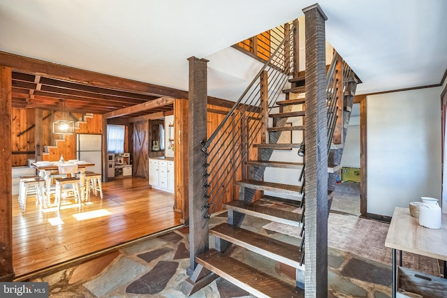 staircase featuring hardwood / wood-style floors, wood walls, and ornate columns