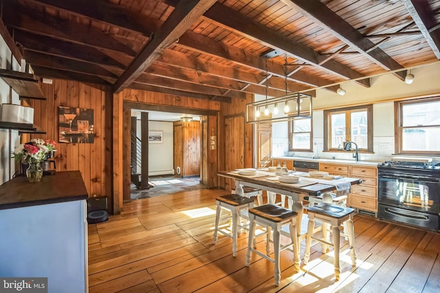 kitchen featuring wooden ceiling, wood walls, light wood-style floors, beamed ceiling, and black gas range oven