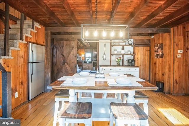 kitchen featuring light wood-style flooring, freestanding refrigerator, beamed ceiling, and wooden walls