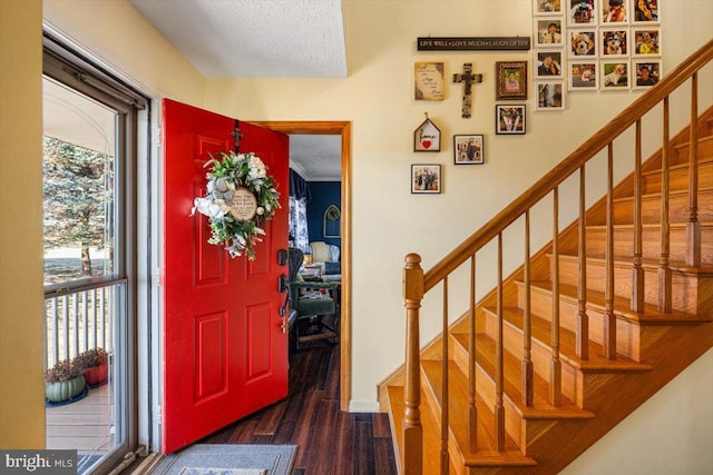 foyer featuring a textured ceiling, wood finished floors, and stairs