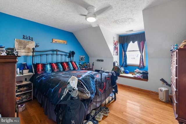 bedroom with visible vents, a ceiling fan, vaulted ceiling, a textured ceiling, and hardwood / wood-style floors