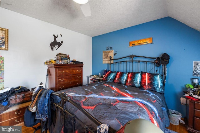 bedroom with a textured ceiling, a ceiling fan, vaulted ceiling, and wood finished floors