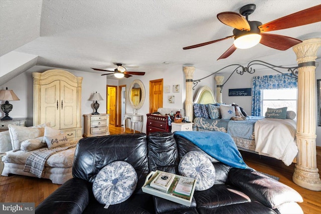 bedroom with a ceiling fan, decorative columns, a textured ceiling, and wood finished floors