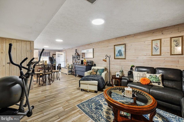 living area with wood walls, a textured ceiling, and wood finished floors