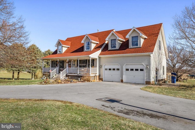 new england style home featuring driveway, an attached garage, and a porch