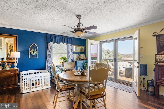 dining space featuring wood-type flooring, ornamental molding, ceiling fan, a textured ceiling, and baseboards