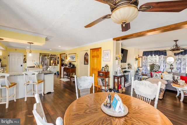 dining space featuring ceiling fan, ornamental molding, dark wood-style flooring, and a textured ceiling