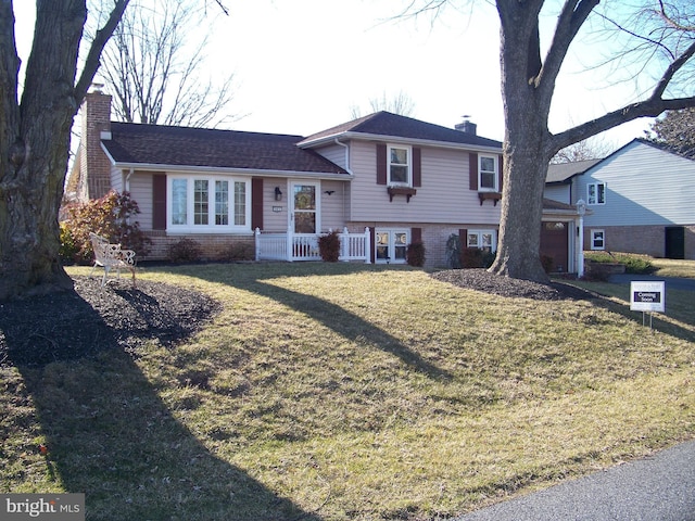 tri-level home featuring brick siding, a chimney, and a front yard