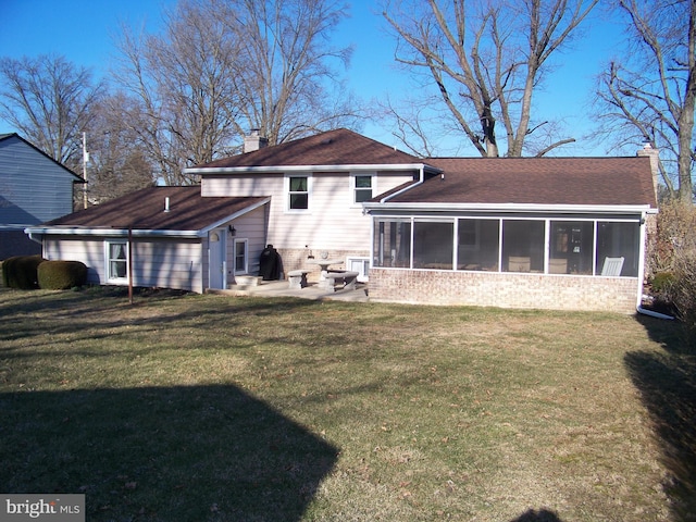 rear view of property with a shingled roof, a sunroom, a yard, a chimney, and a patio area