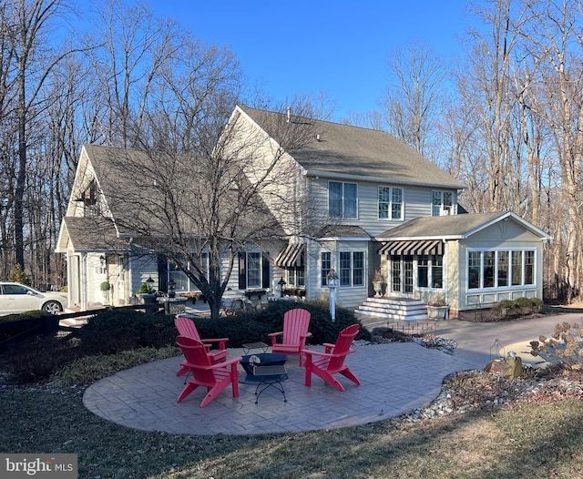 rear view of property with a fire pit, a shingled roof, and a patio area