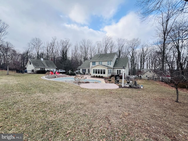 rear view of property featuring a patio, a yard, fence, and a covered pool