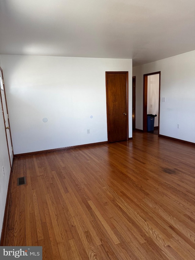 empty room with baseboards, visible vents, and wood finished floors