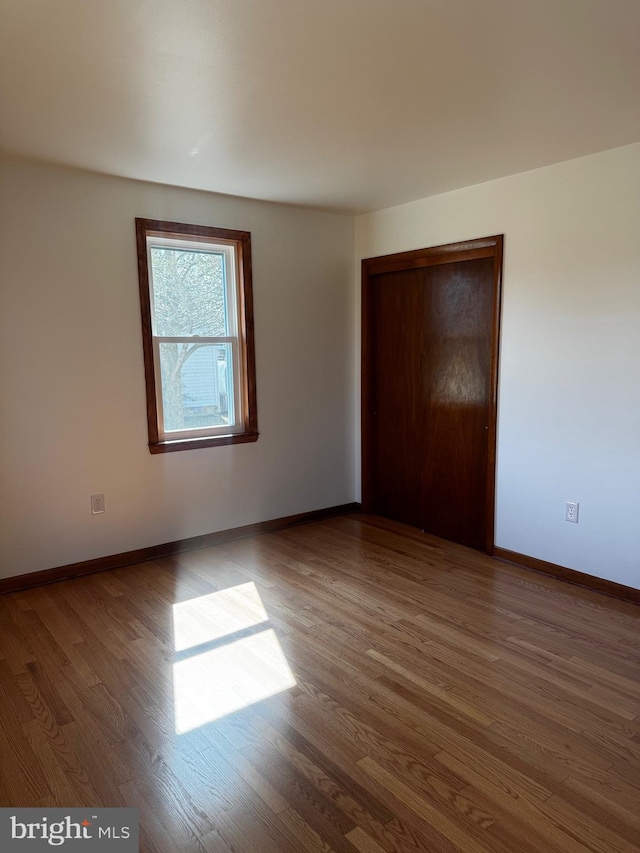 unfurnished bedroom with a closet, wood finished floors, and baseboards